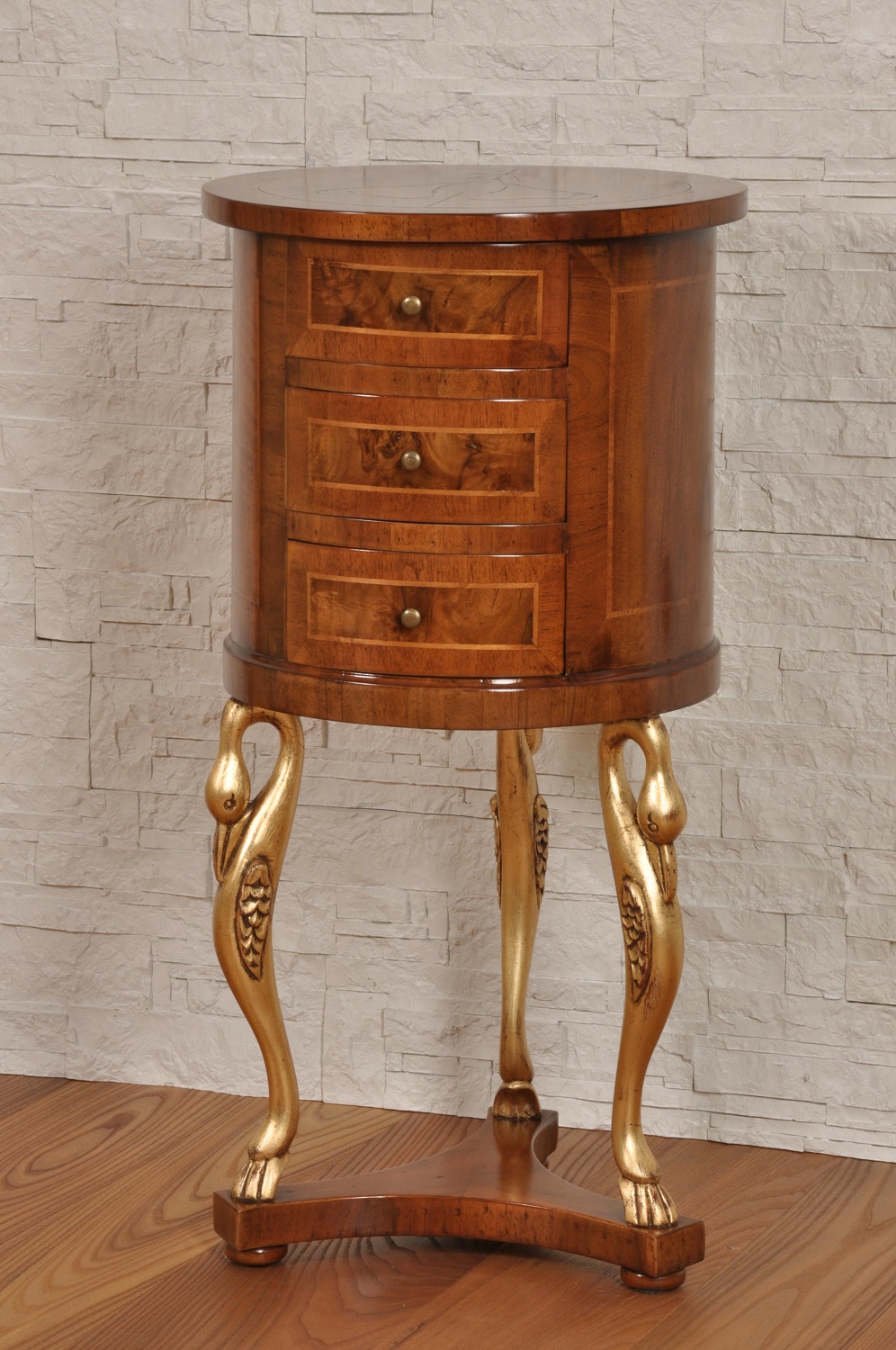 Comodino tondo con 3 cassetti, intarsiato in radica di noce con 3 gambe di  sostegno a forma “di cigno” intagliate e scolpite a mano in stile Luigi  XIV, dorate in foglia oro.
