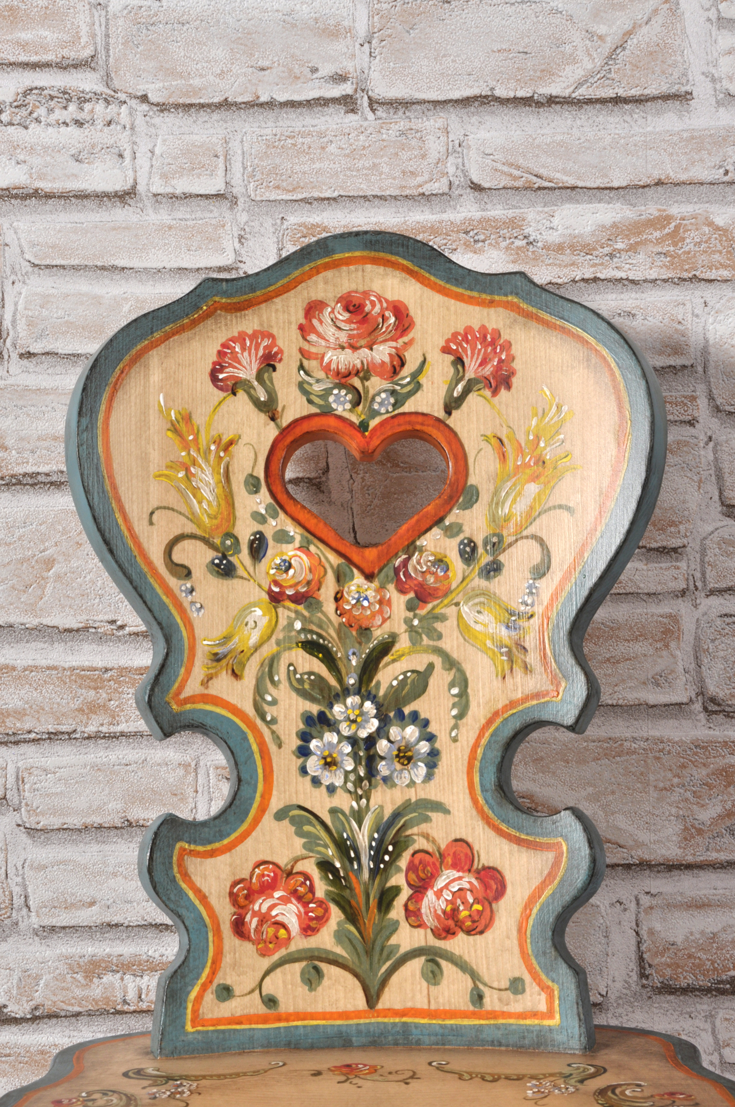 sagomatura dello schienale ricca di decorazioni con mazzi di fiori dai colori vivaci della sedia tirolese dipinta a mano nello stile classico trentino