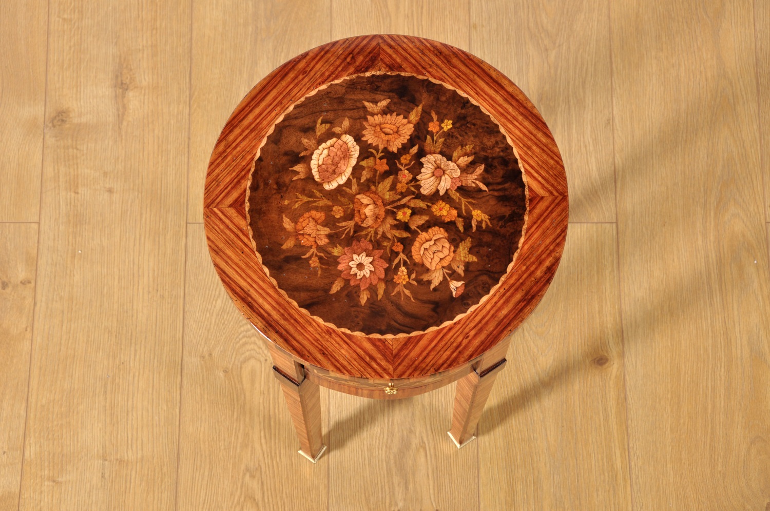tavolino rotondo intarsiato del 1700 con disegni floreali e geometrici in essenze pregiate di acero noce americano palissandro ebano e bois de rose le 4 gambe sono a spillo coniche con un cassetto