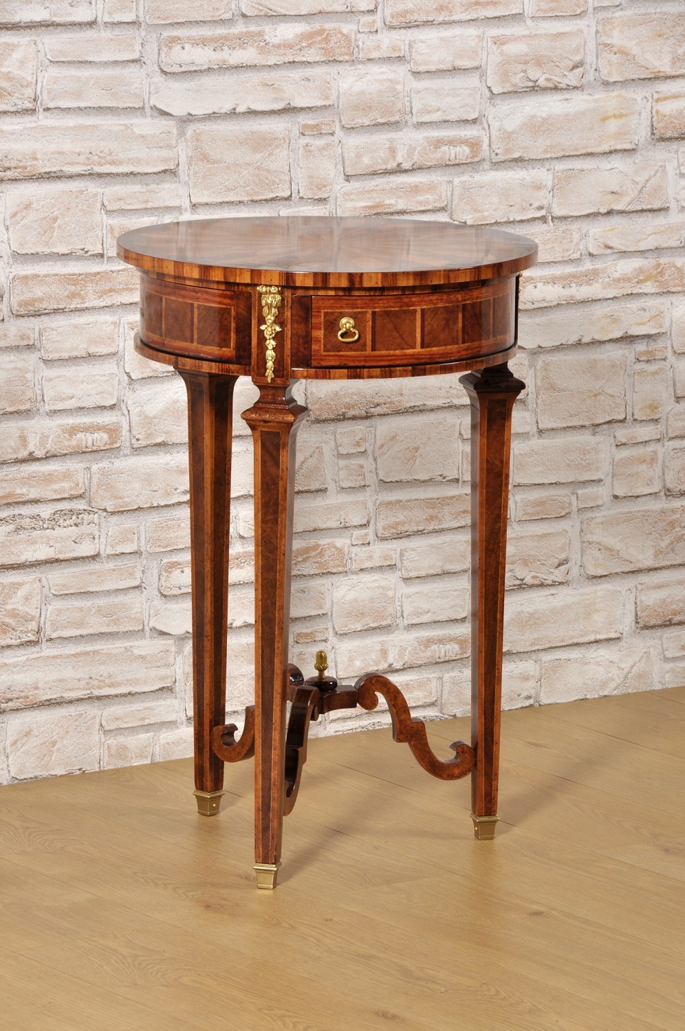 tavolino intarsiato in legni pregiati esotici di forma rotonda prodotto nello stile classico Luigi XVI Neoclassico Maggiolini con 3 gambe tronco piramidali e cassetti segreti a ventaglio